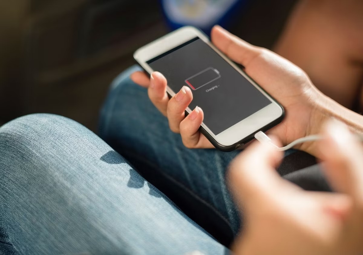 نحوه استفاده از Optimized Battery Charging در آیفون 1 یک شخص آیفونی بدون برق در دست دارد که در حال شارژ شدن است