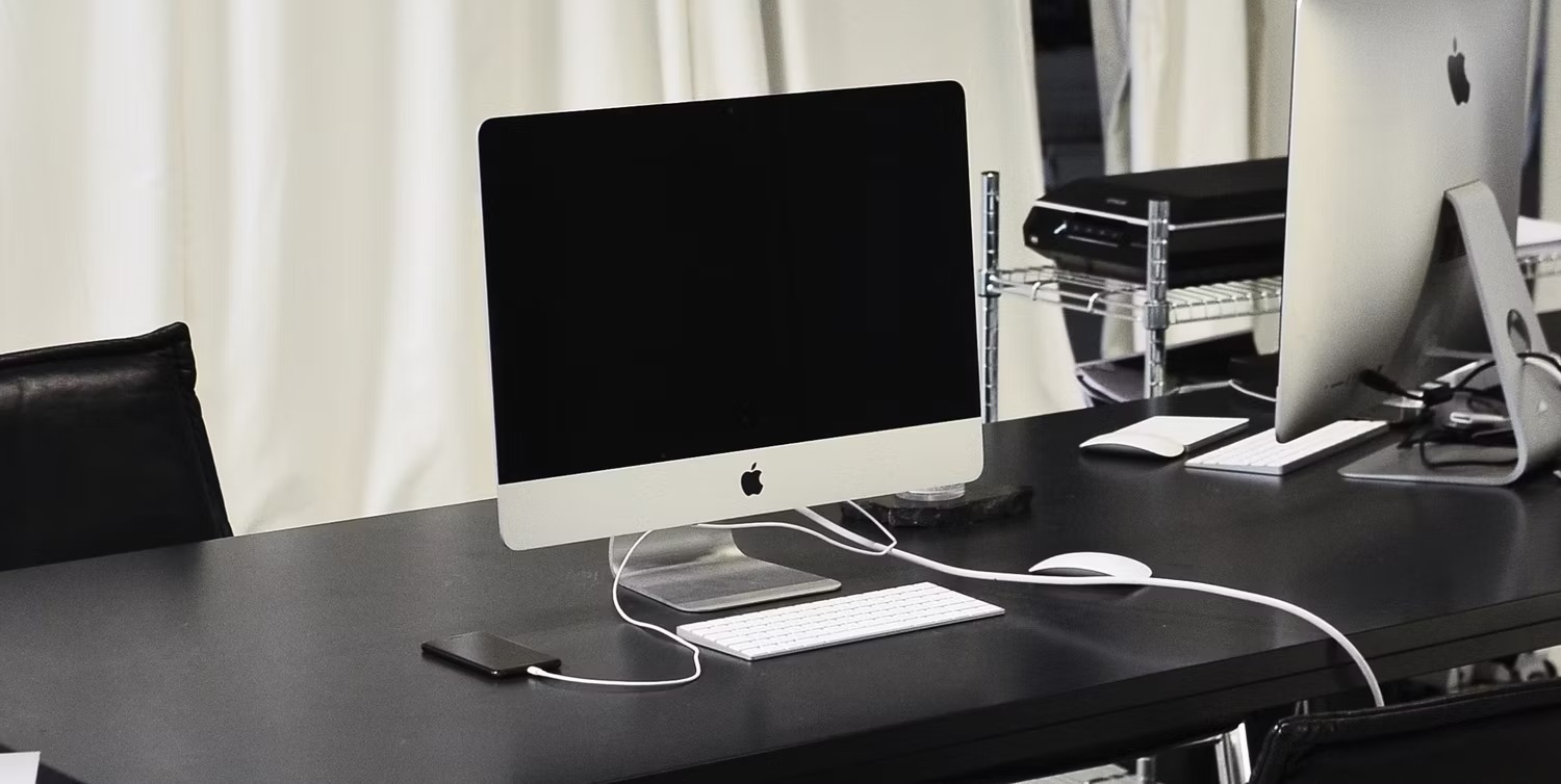 آیفون در کنار iMac روی میز شارژ می شود