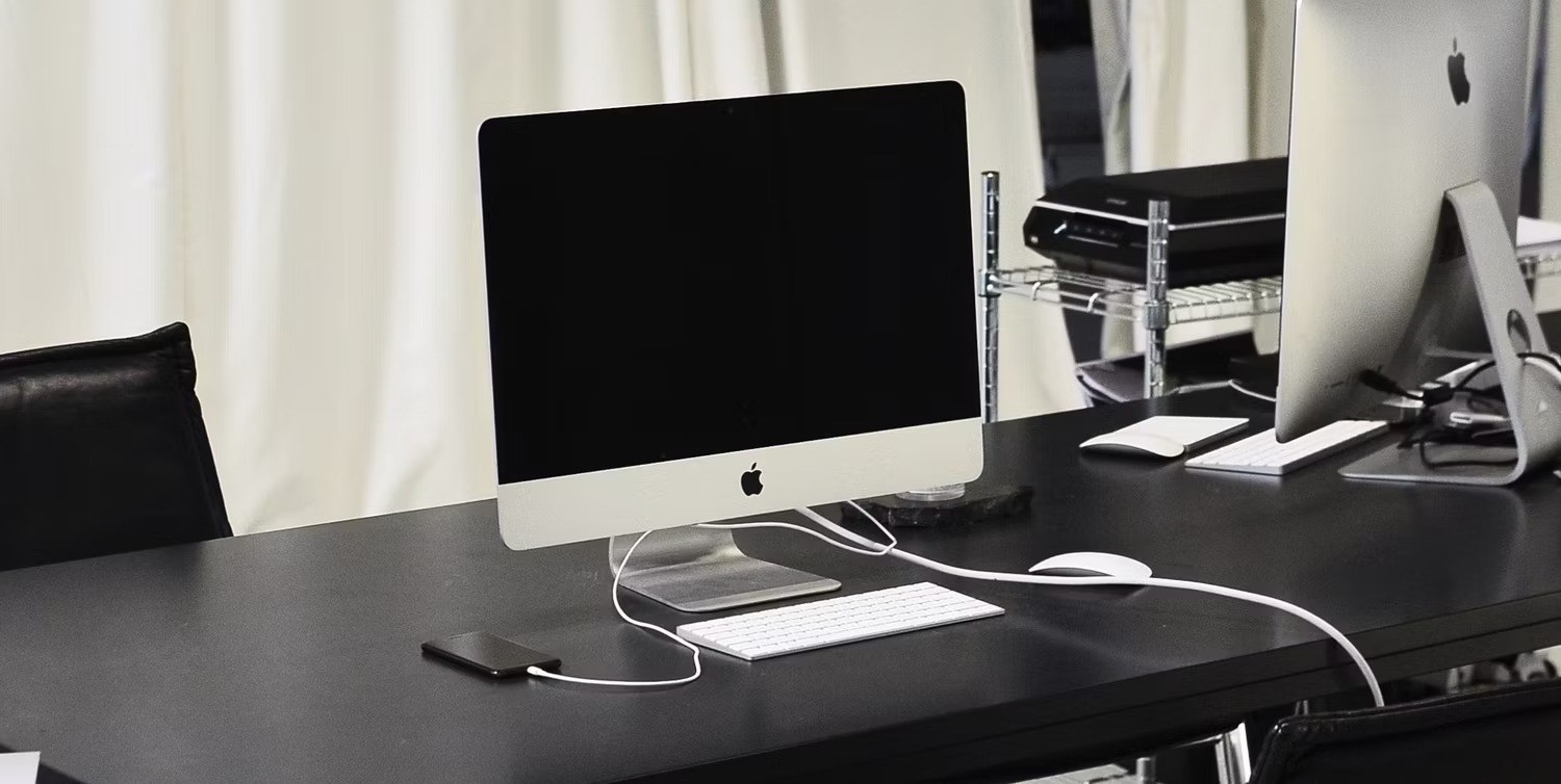 نحوه استفاده از Optimized Battery Charging در آیفون 2 آیفون در کنار iMac روی میز شارژ می شود