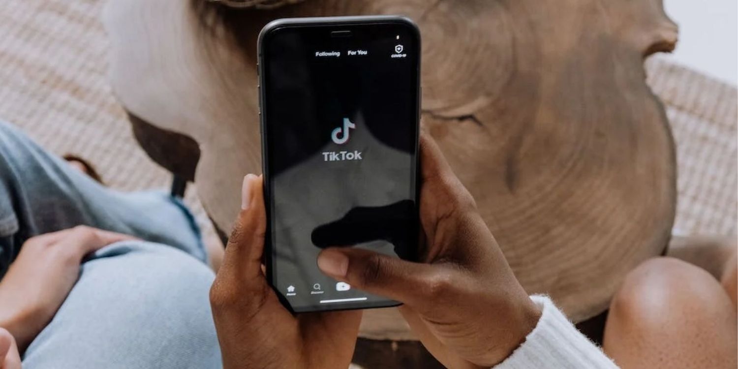 شخصی که گوشی هوشمندی در دست دارد و برنامه TikTok روی صفحه باز است
