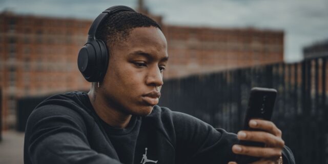 مرد جوان در حال گوش دادن به موسیقی با تلفن همراه با هدفون